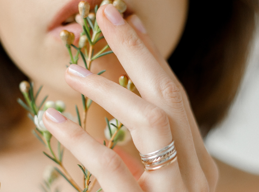 close-up-womans-hand-with-stacked-sliver-gold-rings-holding-flowers
