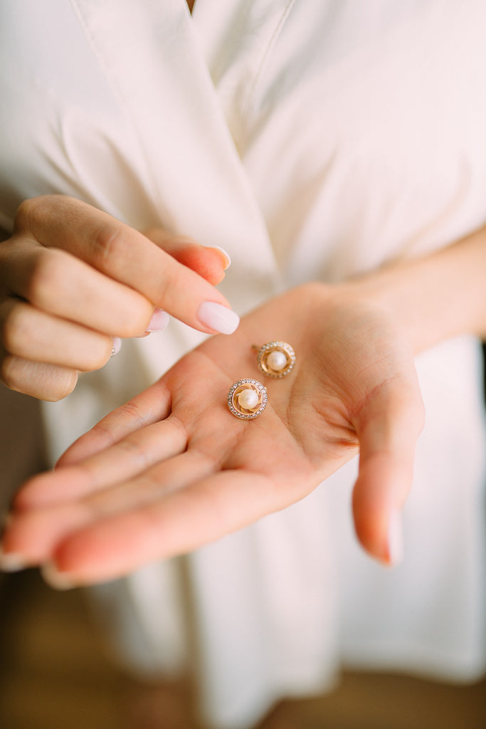 womans-open-palm-holding-two-diamond-pearl-stud-earrings