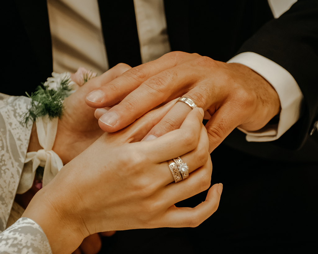 woman with engagement and wedding band placing wedding ring on man's finger